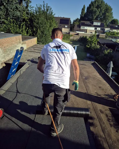 Dakdekker van Leermans rolt dakbedekking uit op een plat dak